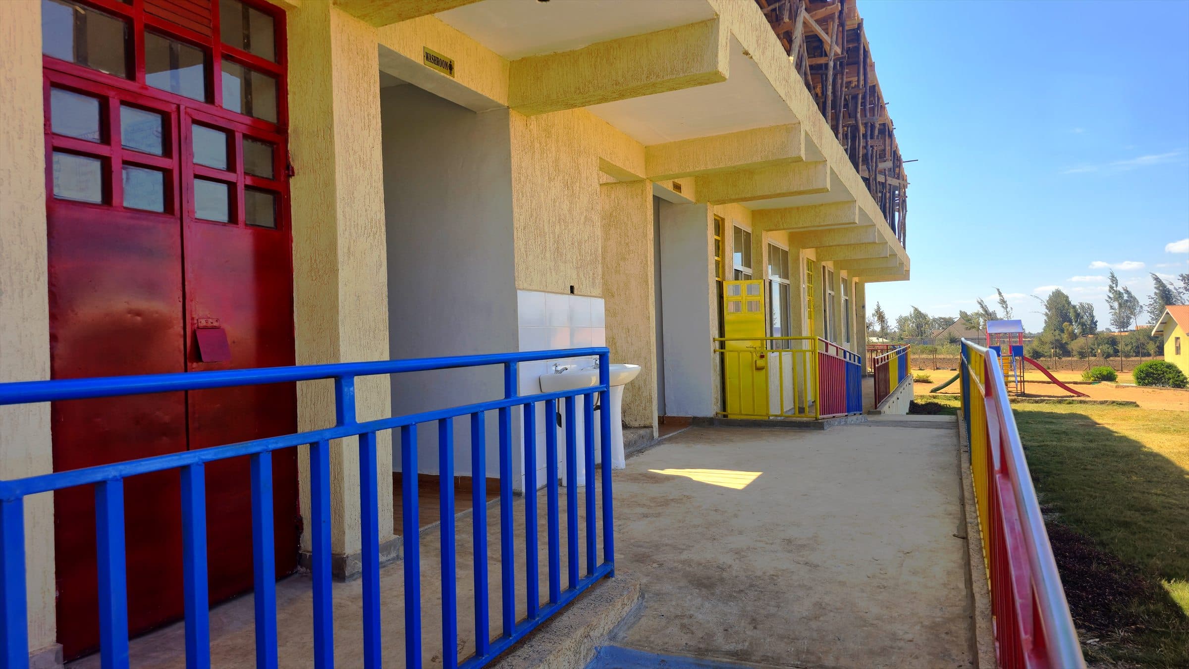 A covered walkway with blue safety railings running past Oak Leaf Academy lower primary classrooms.